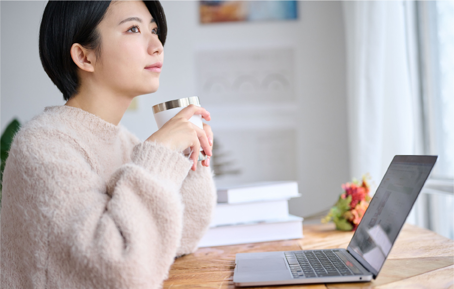 タンブラーを使ってデスクでくつろぐ女性